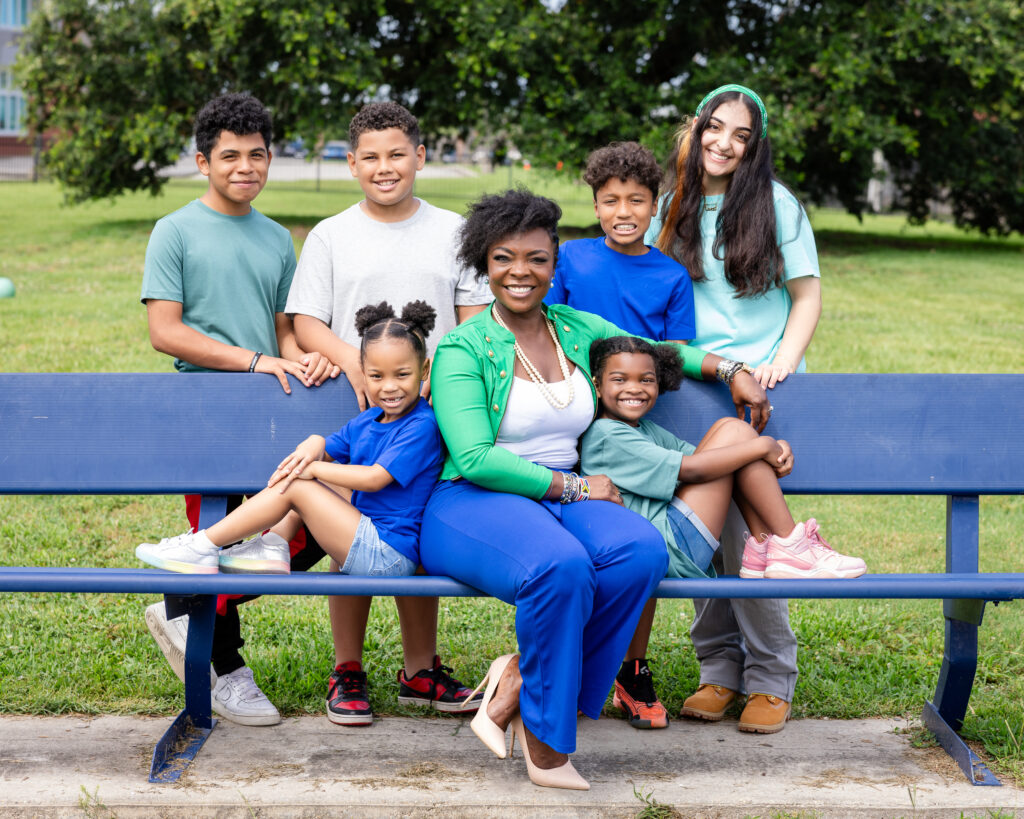 KaTrina Griffin sitting outside on bench with a group of kids